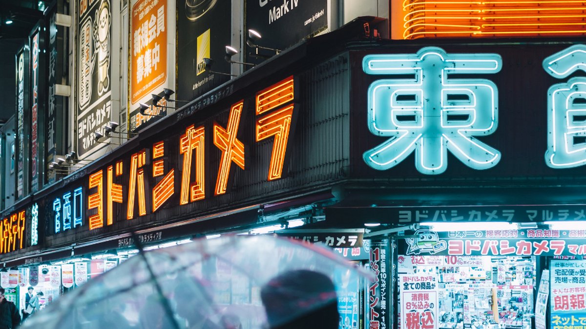 Neon electronics-store signs on a Tokyo street at night