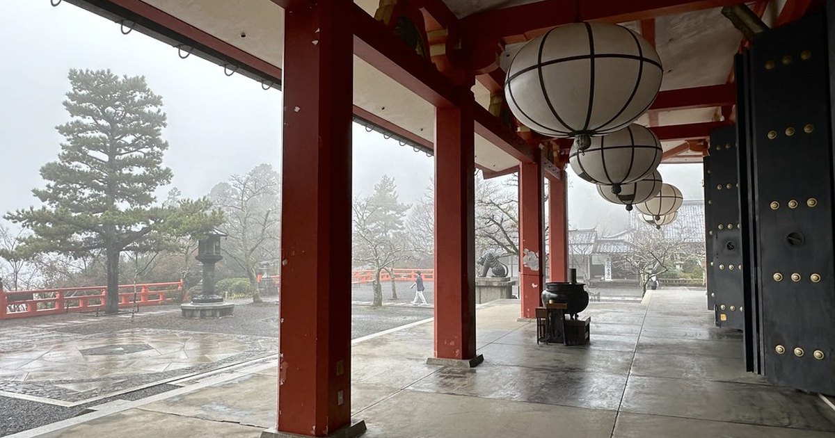 Vermilion pillars and paper lanterns of the Kurama-dera main hall veranda in mountain mist
