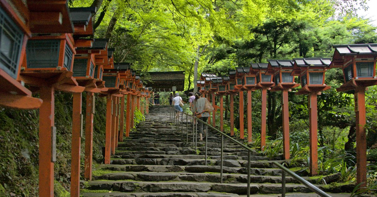Stone stairway lined with red lanterns leading up to Kifune Shrine under green maples