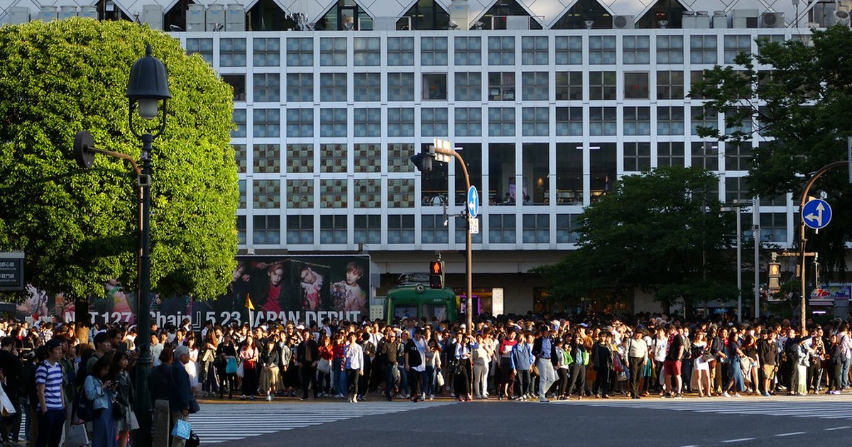 A dense crowd waiting to cross at Shibuya scramble crossing in late-afternoon light