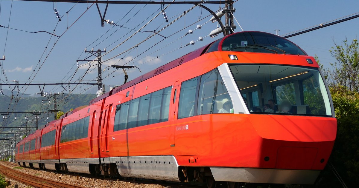 A vermilion Odakyu Romancecar GSE train running on open track with its large front window