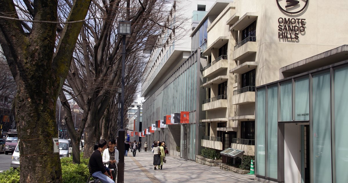 The zelkova-lined sidewalk of Omotesando alongside the long facade of Omotesando Hills