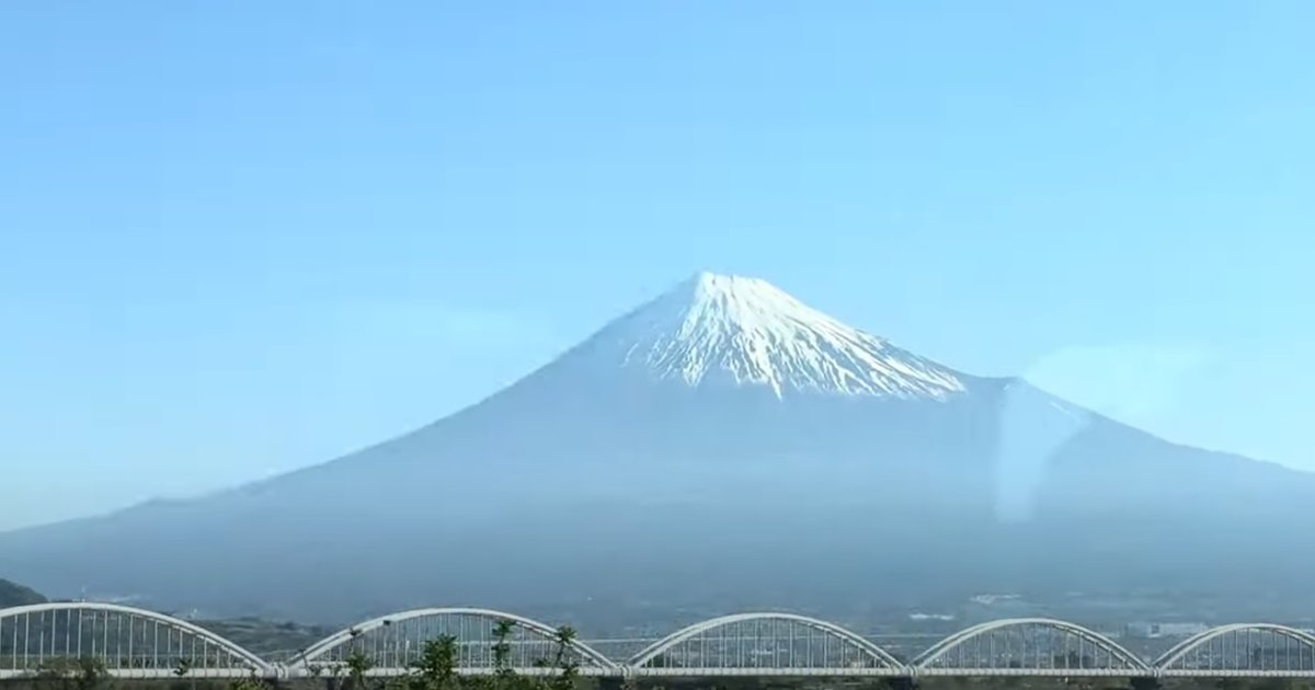Snow-capped Mount Fuji seen from a Tokaido Shinkansen window as the train crosses the Fuji River bridges