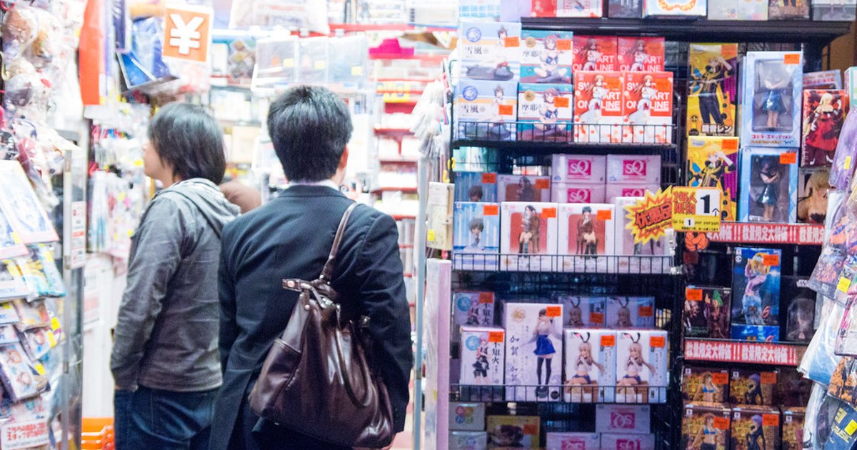 Shoppers browsing dense shelves of boxed anime figures inside an Akihabara store
