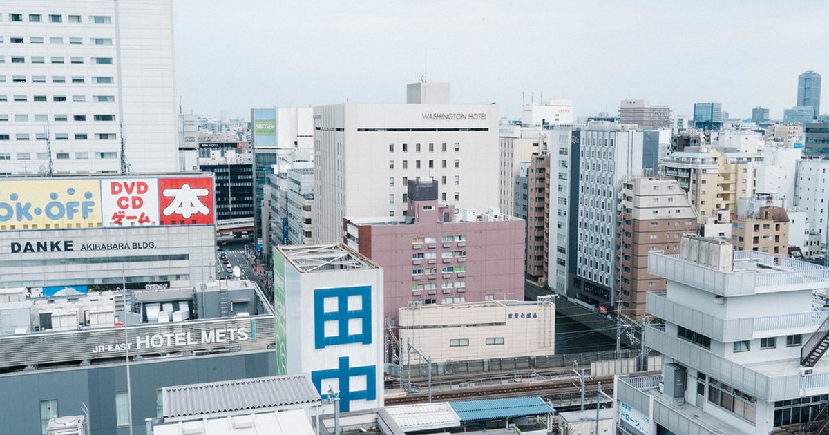 Elevated view over Akihabara rooftops showing shop buildings, office blocks and a train on elevated tracks