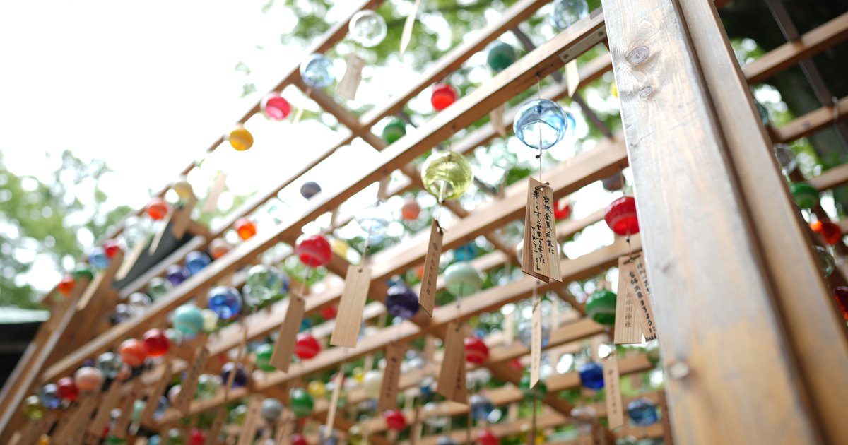 Tunnel of colorful glass wind chimes with handwritten wooden wish tags hanging from a wooden frame at Kawagoe Hikawa Shrine