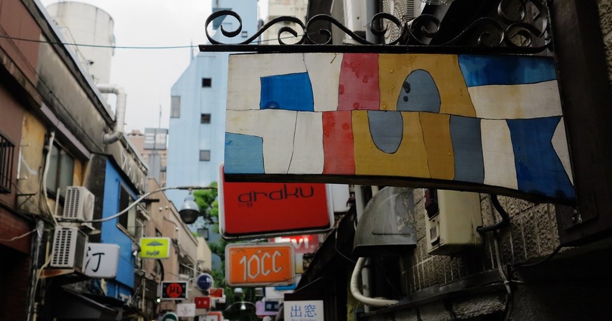 Hand-painted bar signs projecting from the walls of a narrow Golden Gai alley