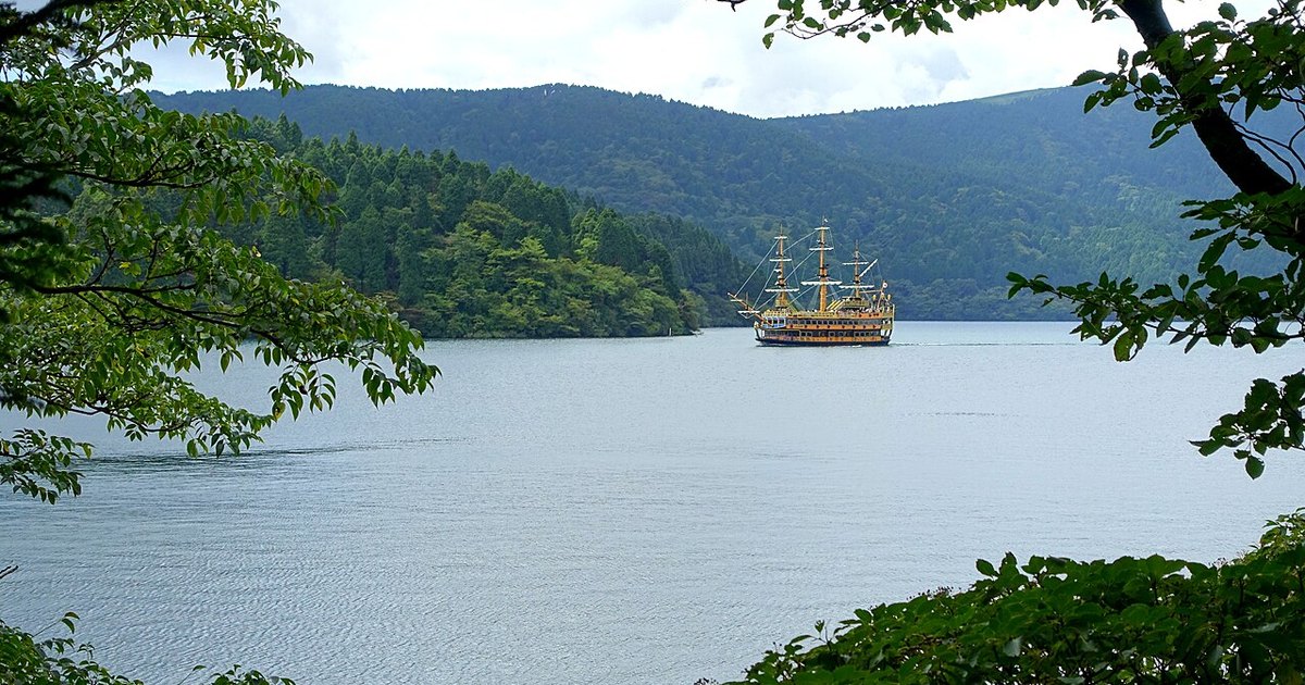 A replica sailing ship crossing Lake Ashi in Hakone with forested hills behind