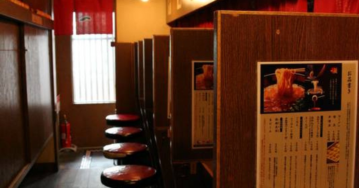 Row of individual solo-dining booths with red stools and wooden partitions at an Ichiran ramen shop in Yokohama