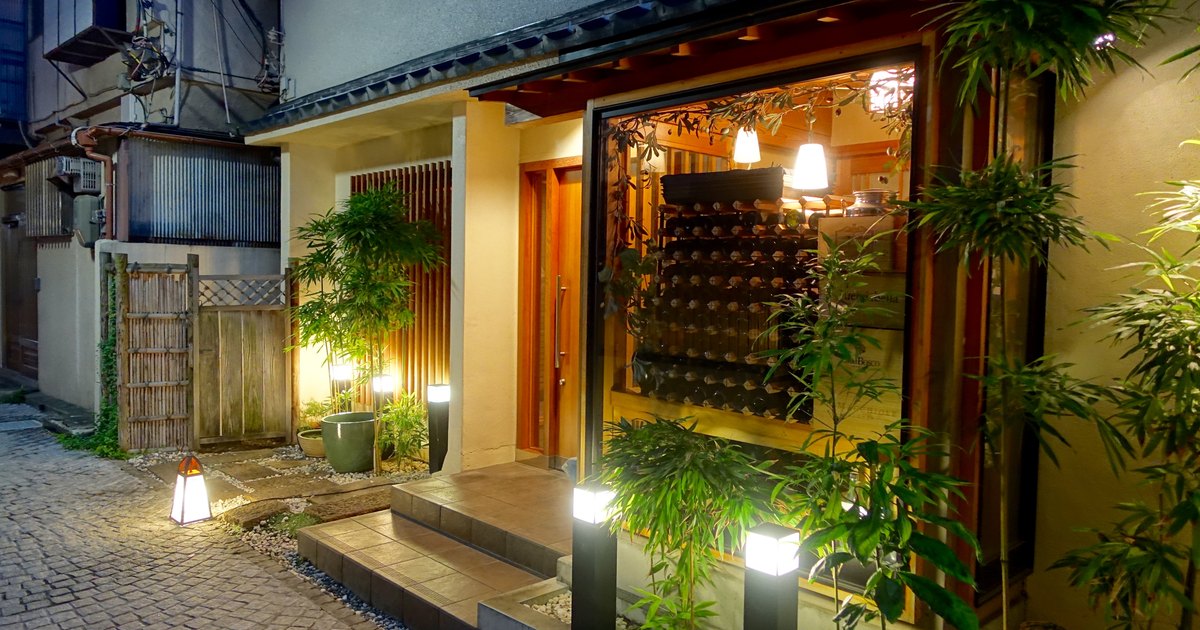 A lantern-lit wooden entrance on a cobbled backstreet in Kagurazaka, Tokyo, at dusk