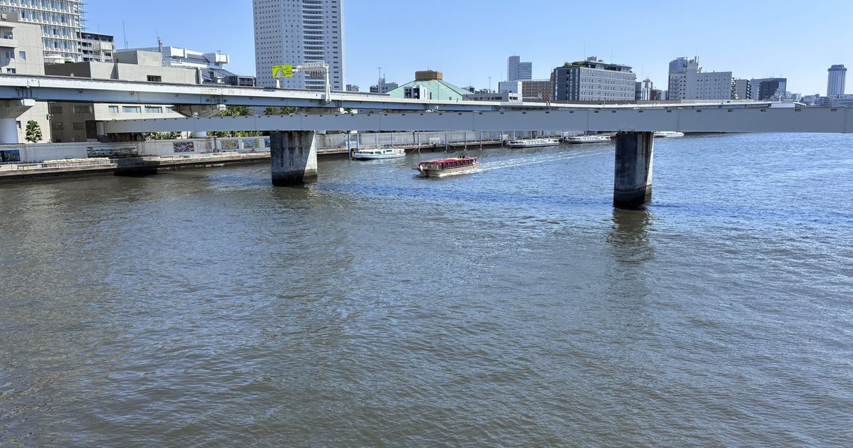 The Sumida River seen from Kuramae Bridge with a small boat passing under an elevated expressway