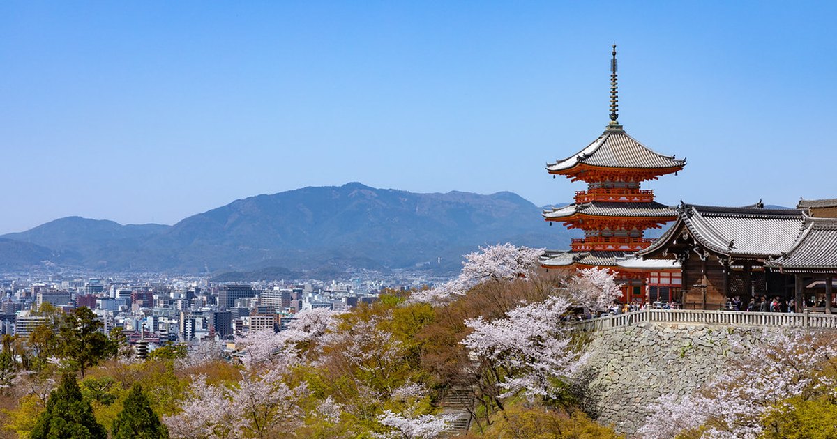 The pagoda and main hall of Kiyomizu-dera above cherry blossom trees with Kyoto behind