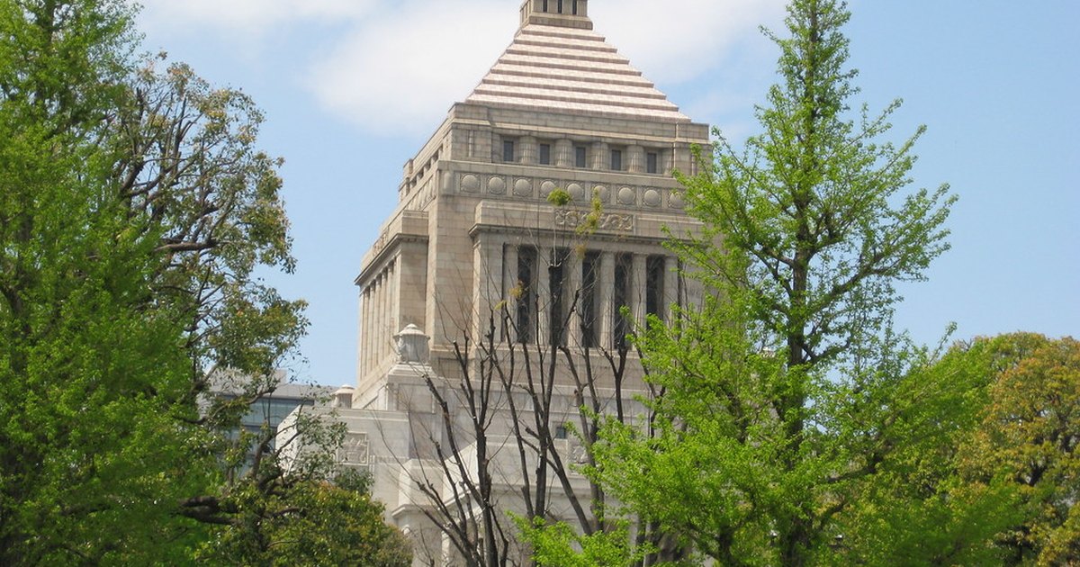 The stepped central tower of Japan's National Diet Building seen through green trees