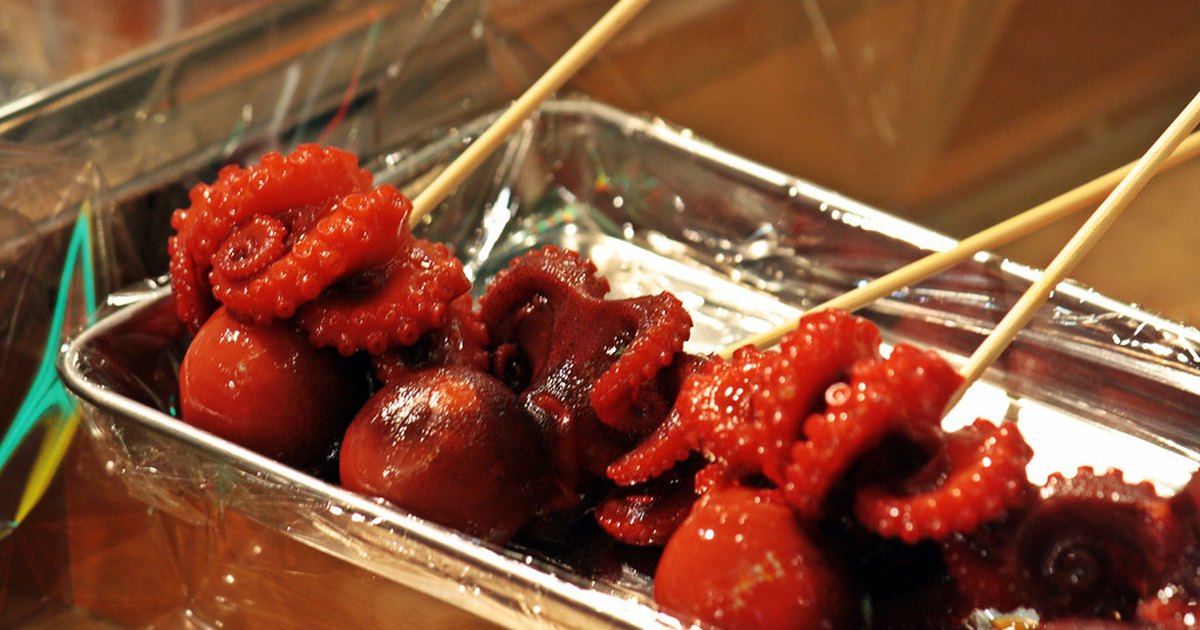 Tako tamago skewers at Nishiki Market, Kyoto: small glazed octopus with a quail egg tucked inside the head, arranged in a metal tray