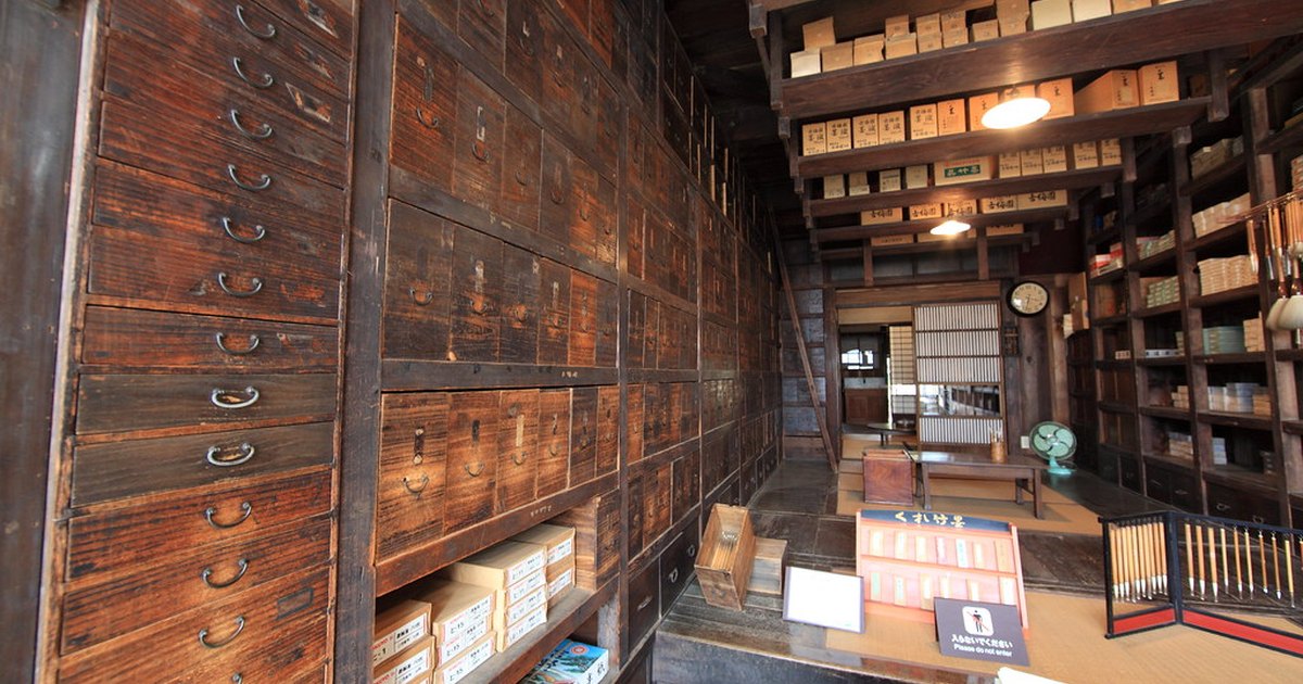 Interior of an old Japanese stationery shop with a wall of small wooden drawers and stacked paper boxes