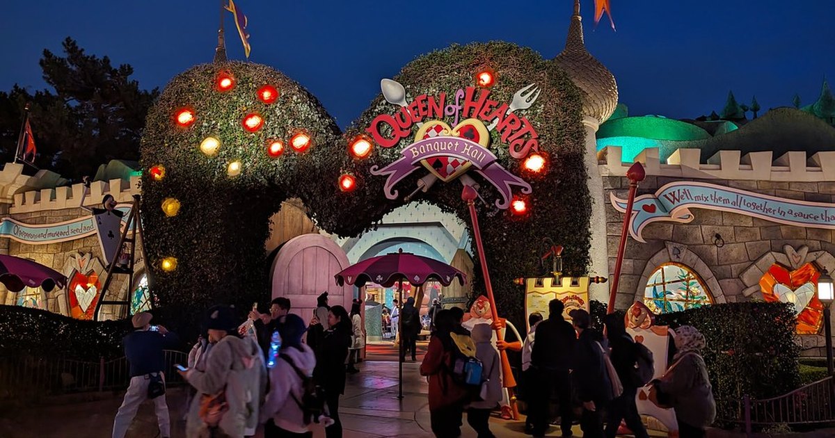 Entrance to Queen of Hearts Banquet Hall restaurant at Tokyo Disneyland at dusk, with topiary arches and illuminated signage