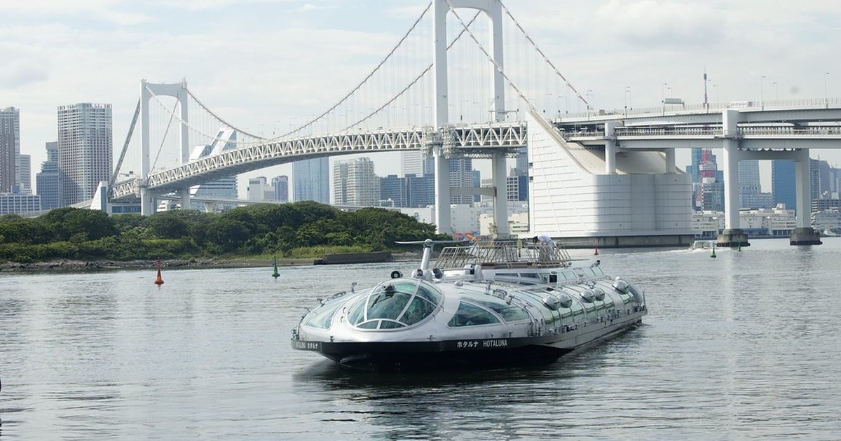 A futuristic cruise boat passing beneath the Rainbow Bridge on Tokyo Bay