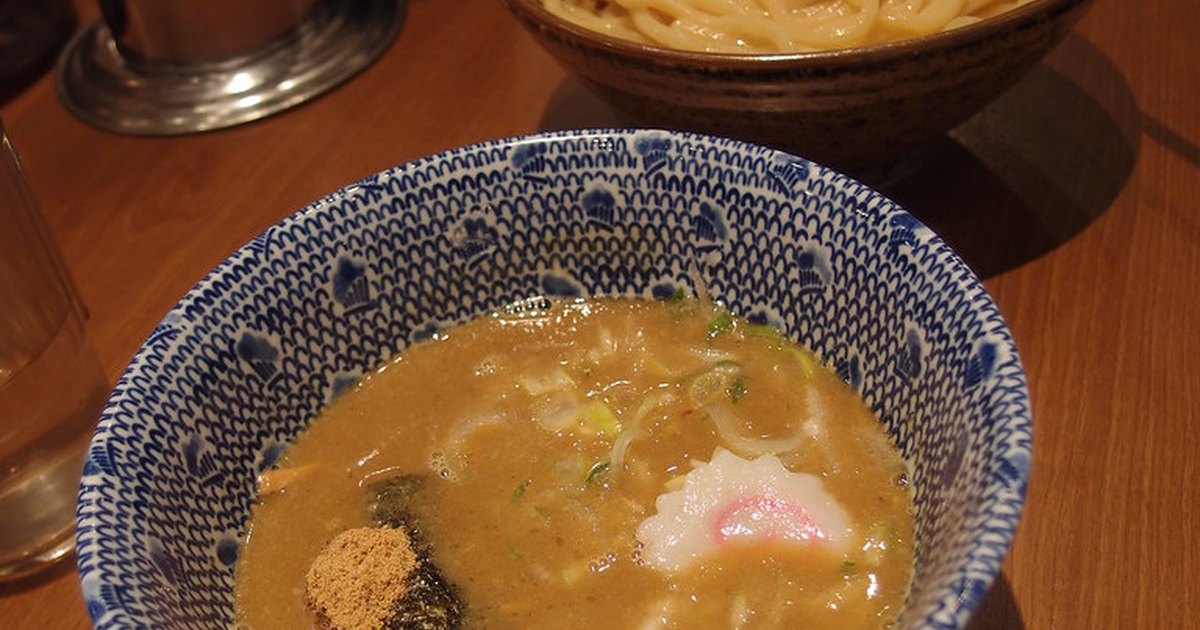 A bowl of thick dipping broth beside a separate bowl of cold noodles topped with a marinated egg