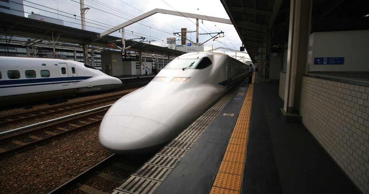 Two white and blue Shinkansen trains at a covered station platform