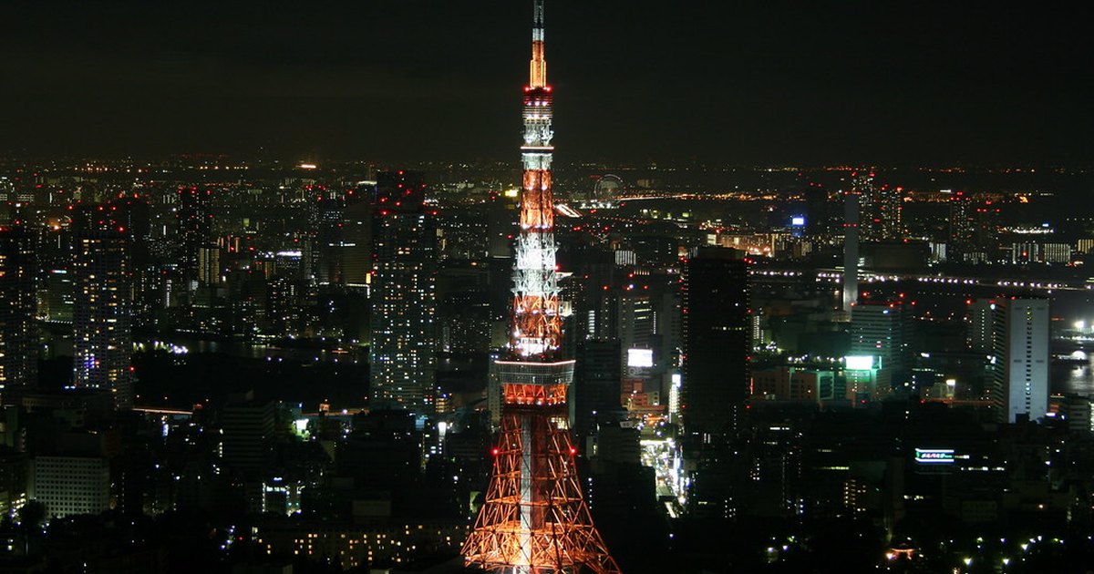 Tokyo Tower lit up at night above the city seen from a high observation deck in Roppongi