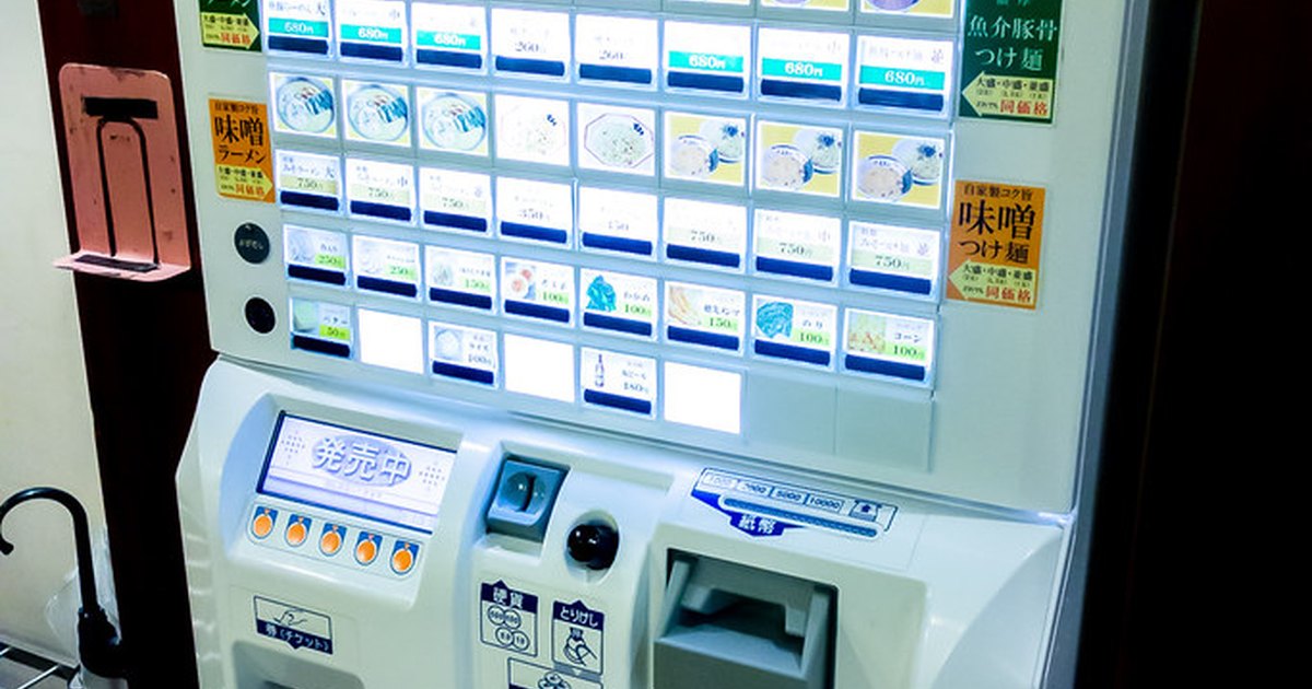 A ramen shop ticket vending machine with rows of buttons showing dish pictures and prices
