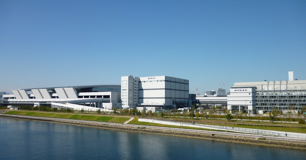 The white sawtooth-roofed buildings of Toyosu Market seen from across the water