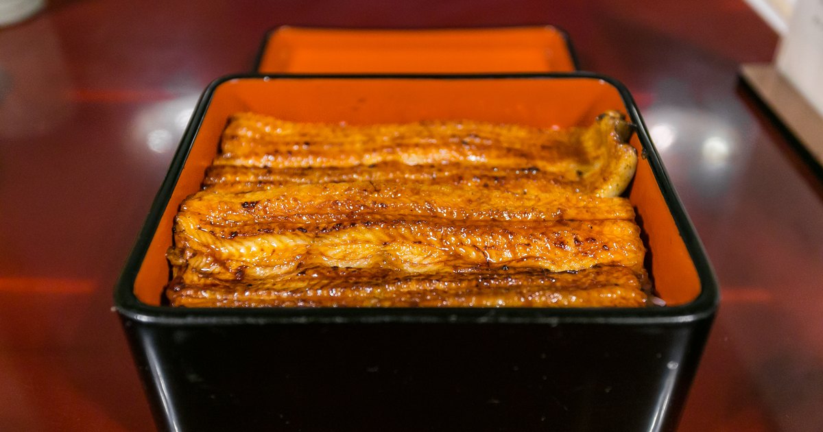 Unaju of glossy charcoal-grilled eel fillets over rice in a black and vermilion lacquered box at a Tokyo unagi restaurant