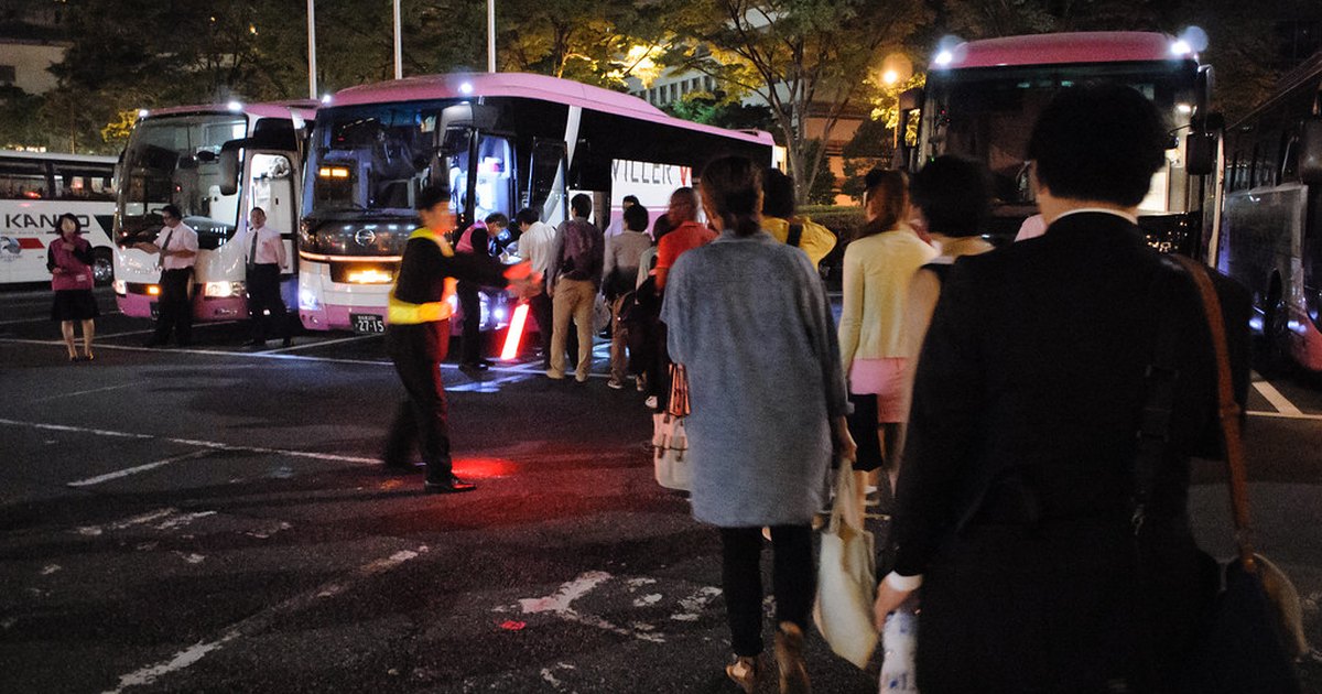 Passengers boarding pink WILLER Express highway buses at a night departure point in Shinjuku