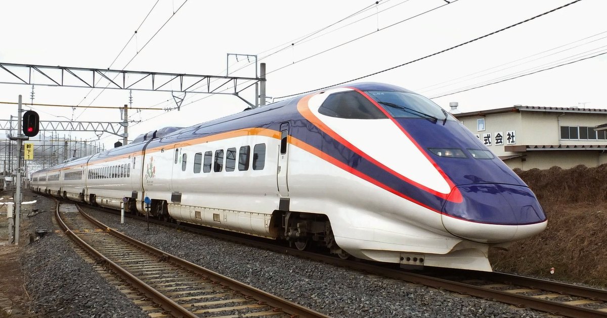 A purple-and-white Yamagata Shinkansen Tsubasa train rounding a curve in winter