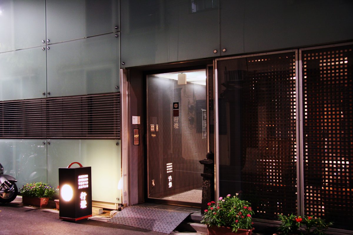 Night view of the Andon Ryokan entrance with a lit lantern sign and potted flowers