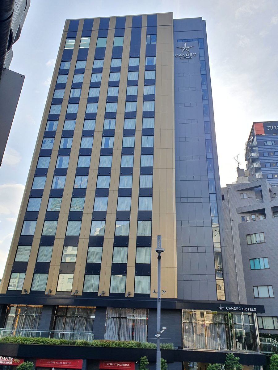 Exterior of Candeo Hotels Tokyo Roppongi, a tall building with gold and dark vertical panels