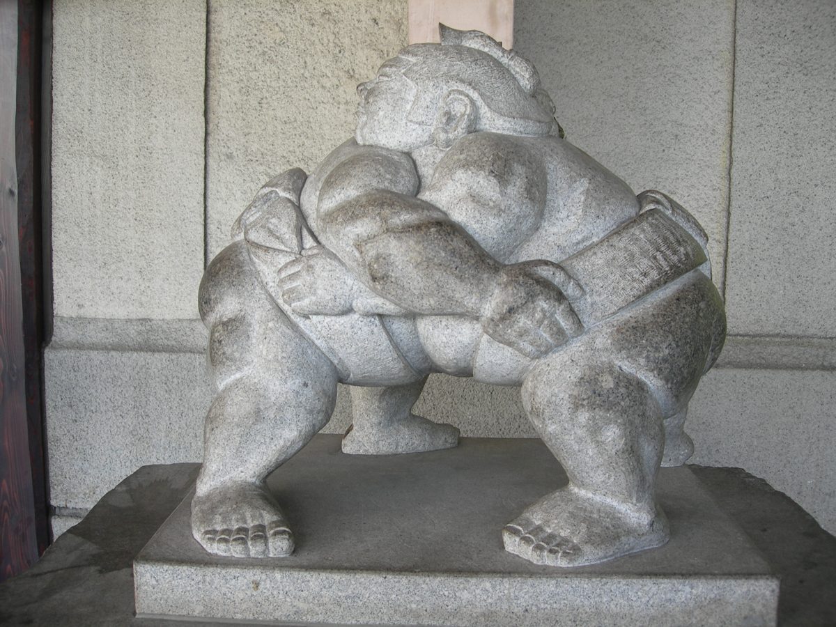 A stone statue of two sumo wrestlers grappling inside Ryogoku Station