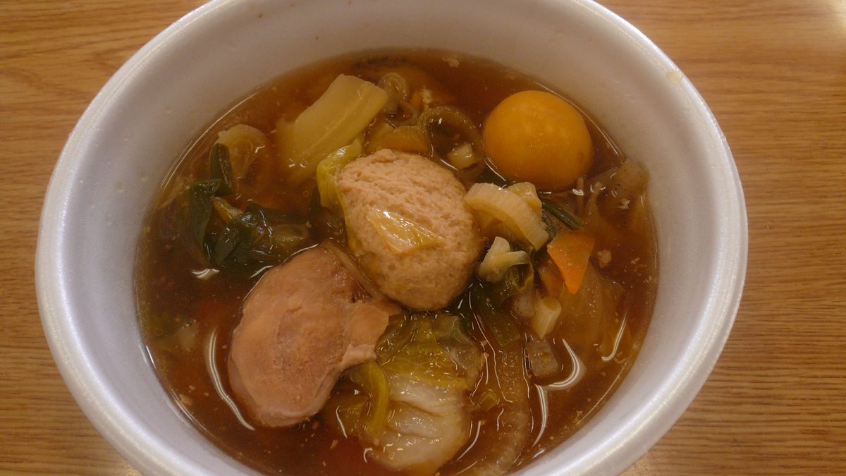 A bowl of chanko nabe with meatballs and vegetables in a brown broth