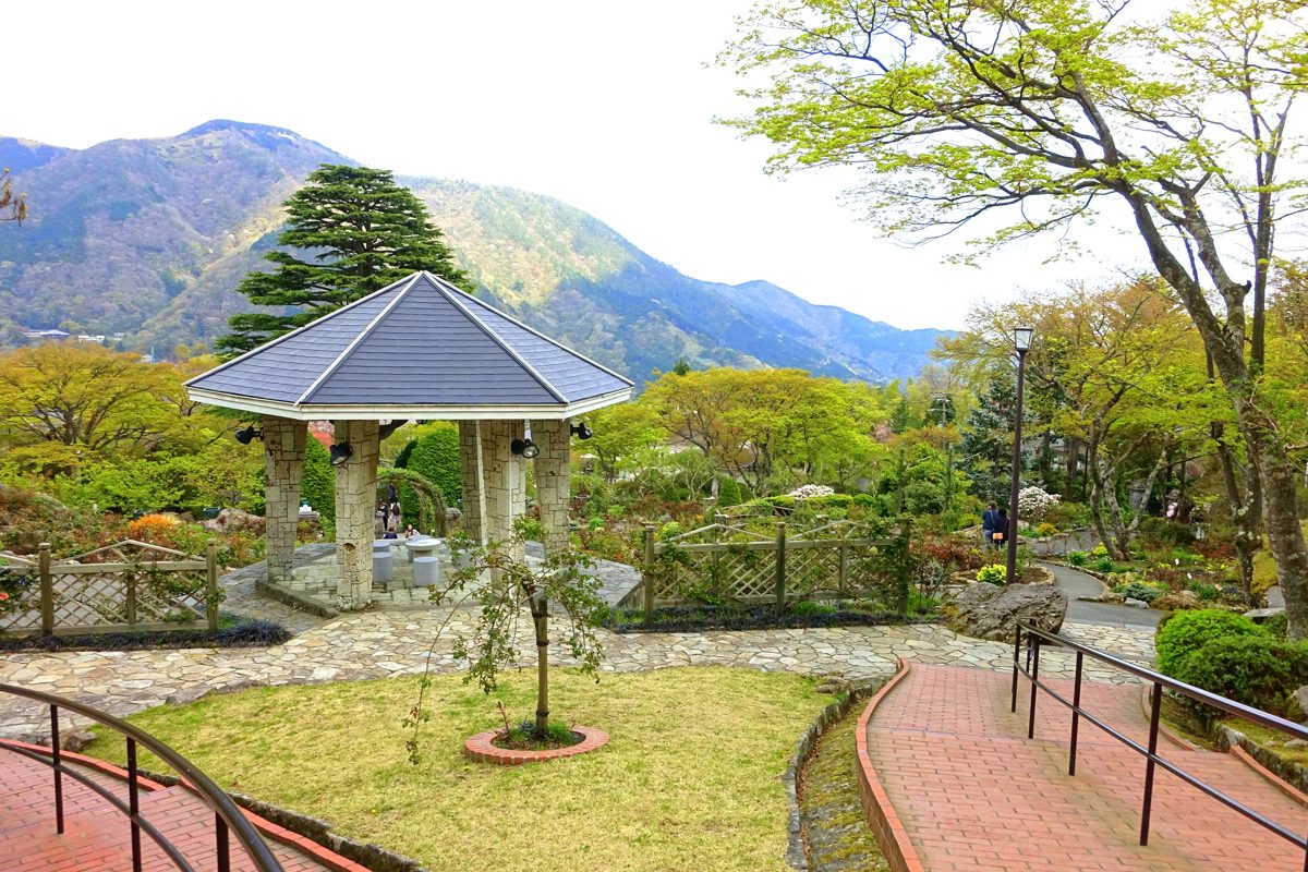 A gazebo and fountain in Gora Park, Hakone, with green mountains behind