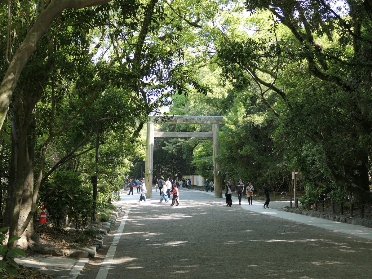 A tree-lined gravel approach and wooden torii gate at Atsuta Jingu in Nagoya