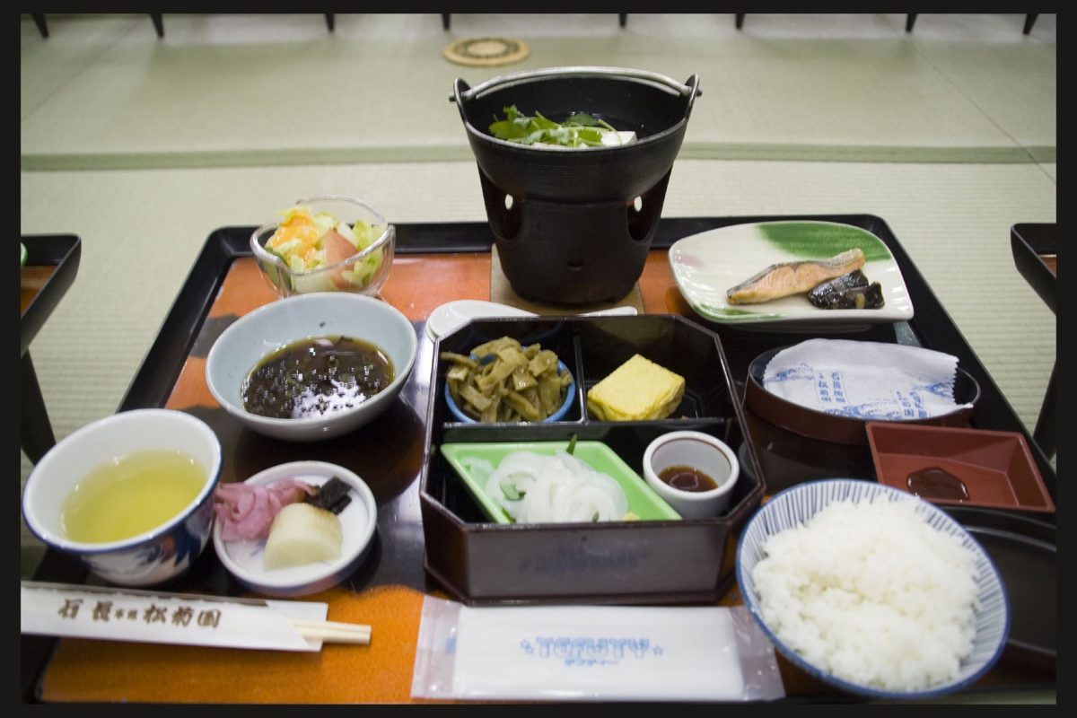 A Japanese breakfast set of rice, grilled fish, small side dishes and a hot pot on a tray in a tatami room