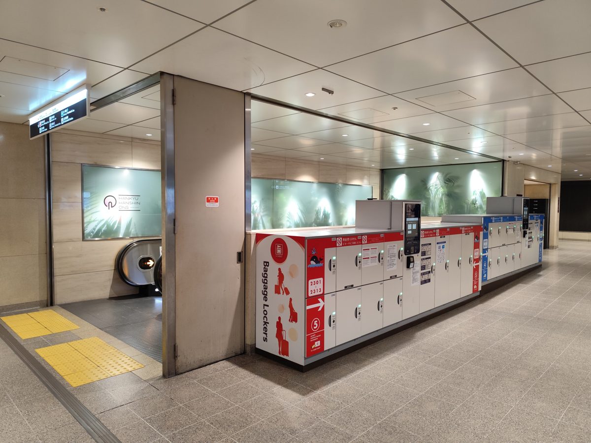 A row of white and red baggage coin lockers in a station concourse
