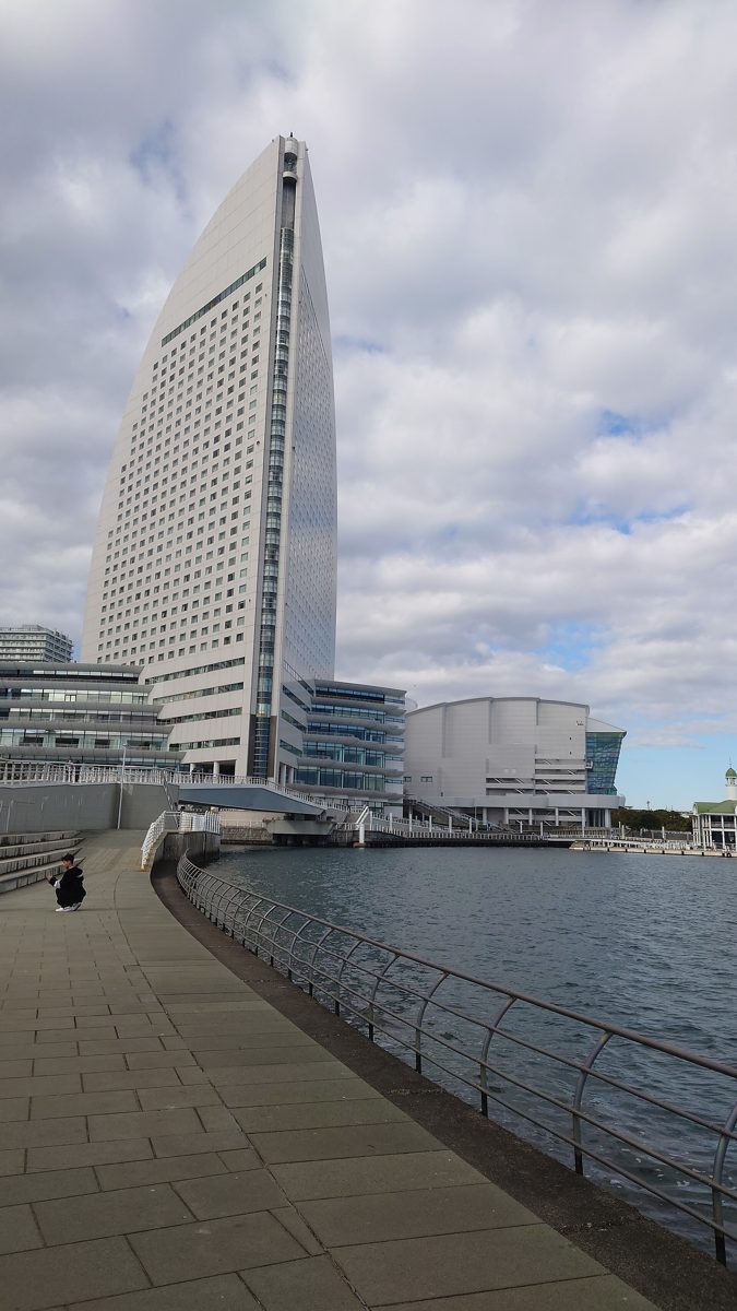 A tall sail-shaped hotel tower beside the harbor in Yokohama