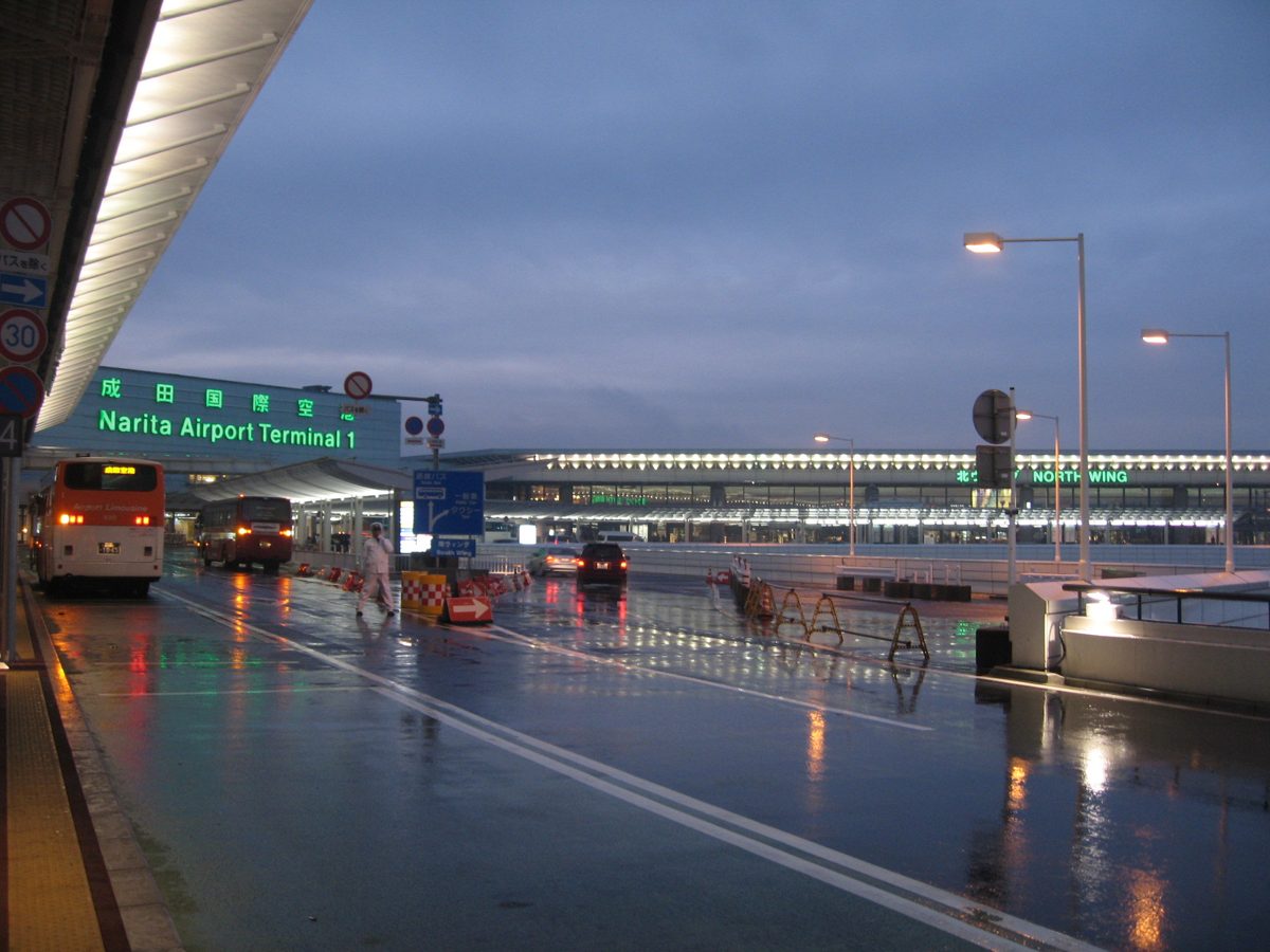 Narita Airport Terminal 1 departure entrance at dusk on a wet road