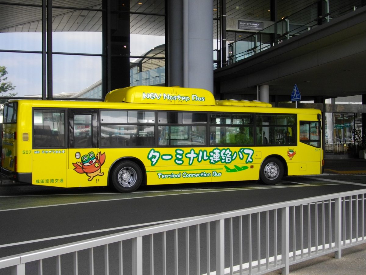 A yellow Narita Airport terminal connection bus parked at a terminal curb