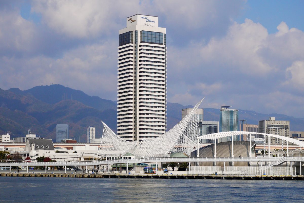 The white tower of Hotel Okura Kobe behind the Kobe Maritime Museum, seen across the harbor