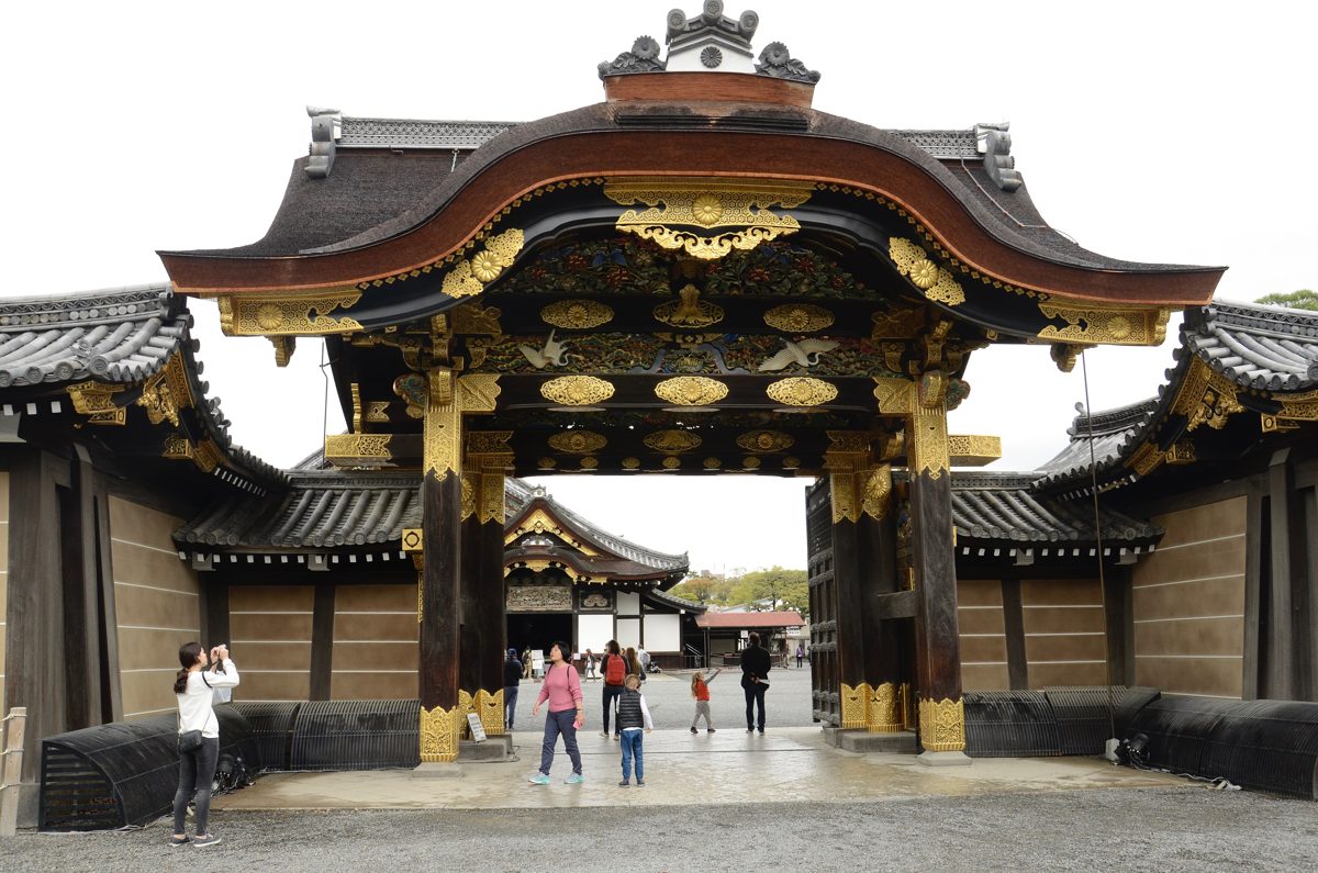 The ornate gilded Karamon gate of Nijo Castle with visitors walking through