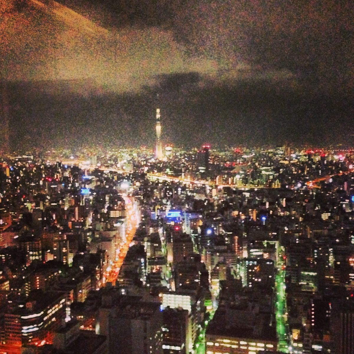 Tokyo at night from high above, with the lit Tokyo Skytree on the horizon