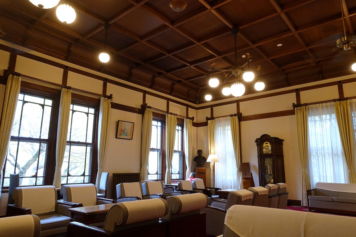 A lounge with a coffered wooden ceiling, tall windows and leather armchairs in Nara Hotel Main Building