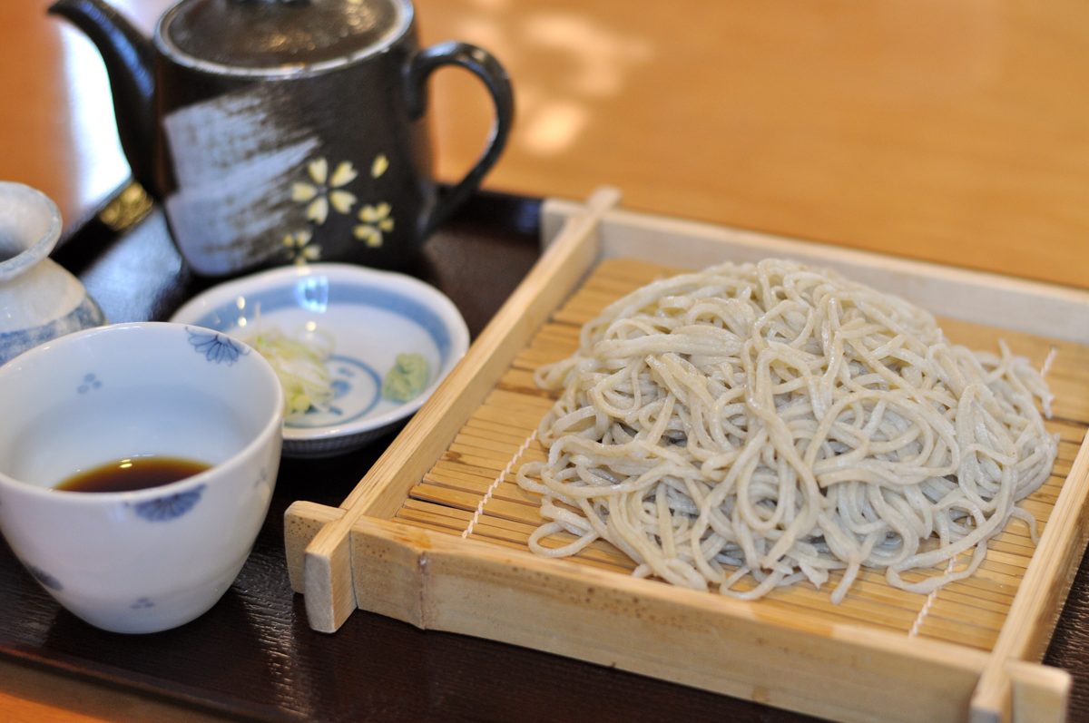 Mori soba on a bamboo tray with dipping sauce, a pot of soba-yu and condiments