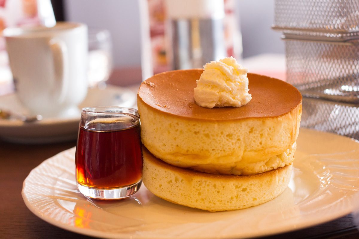 Two thick oven-baked souffle pancakes with butter and a small jug of syrup