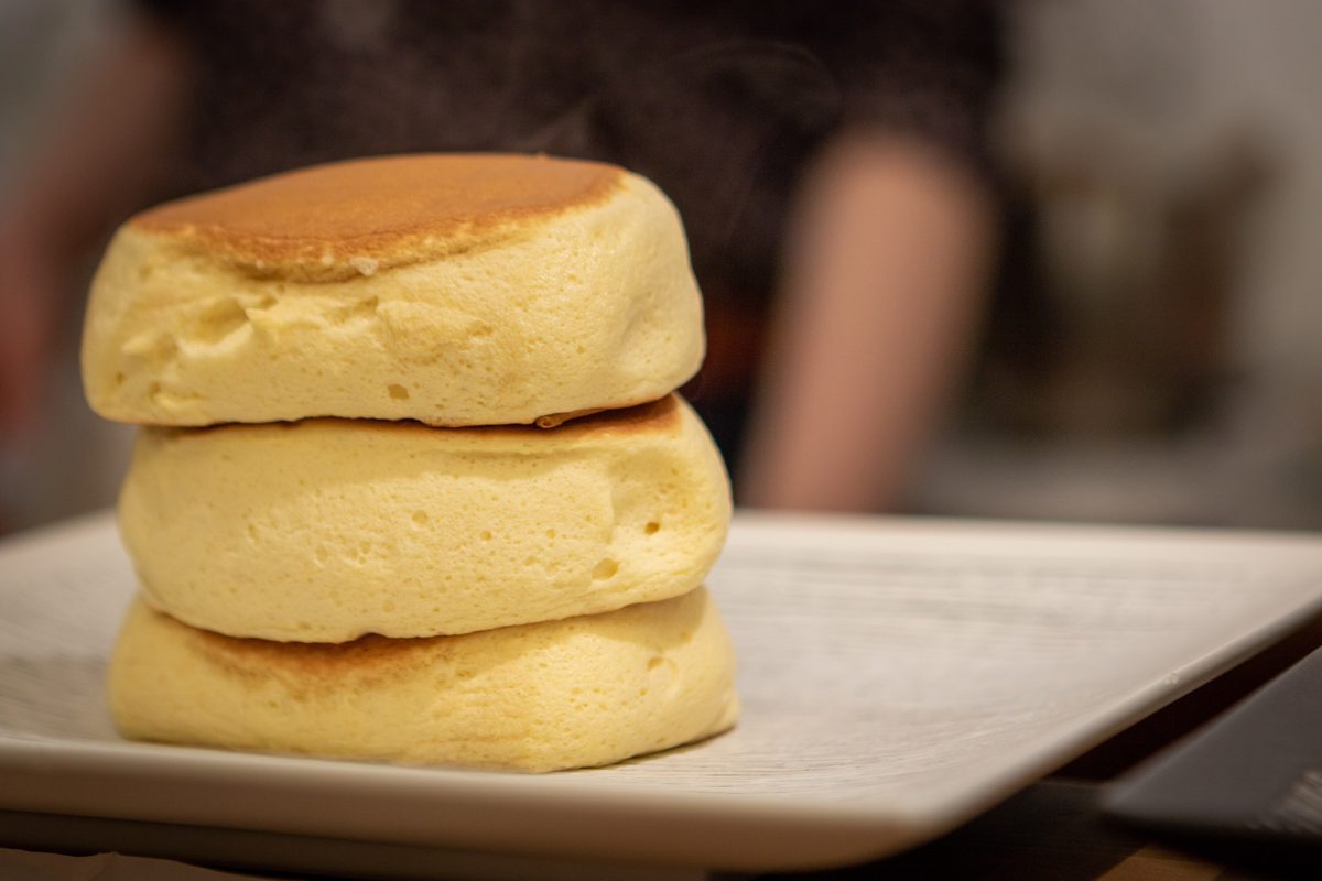 A stack of three tall, fluffy pancakes on a plate