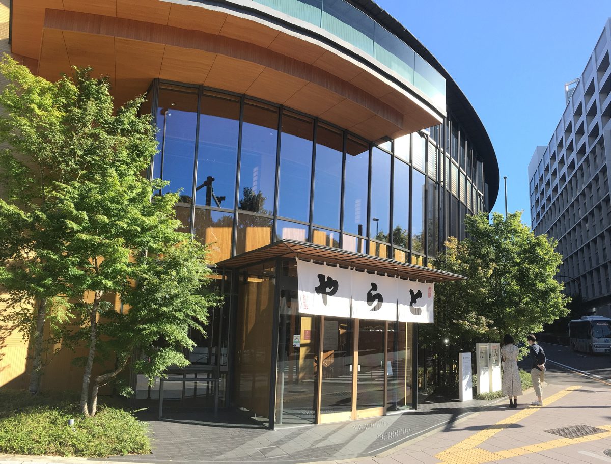 A glass-fronted building with a white noren curtain at its entrance