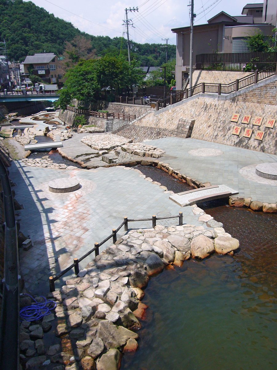 A shallow river with stone banks and steps running through Arima Onsen