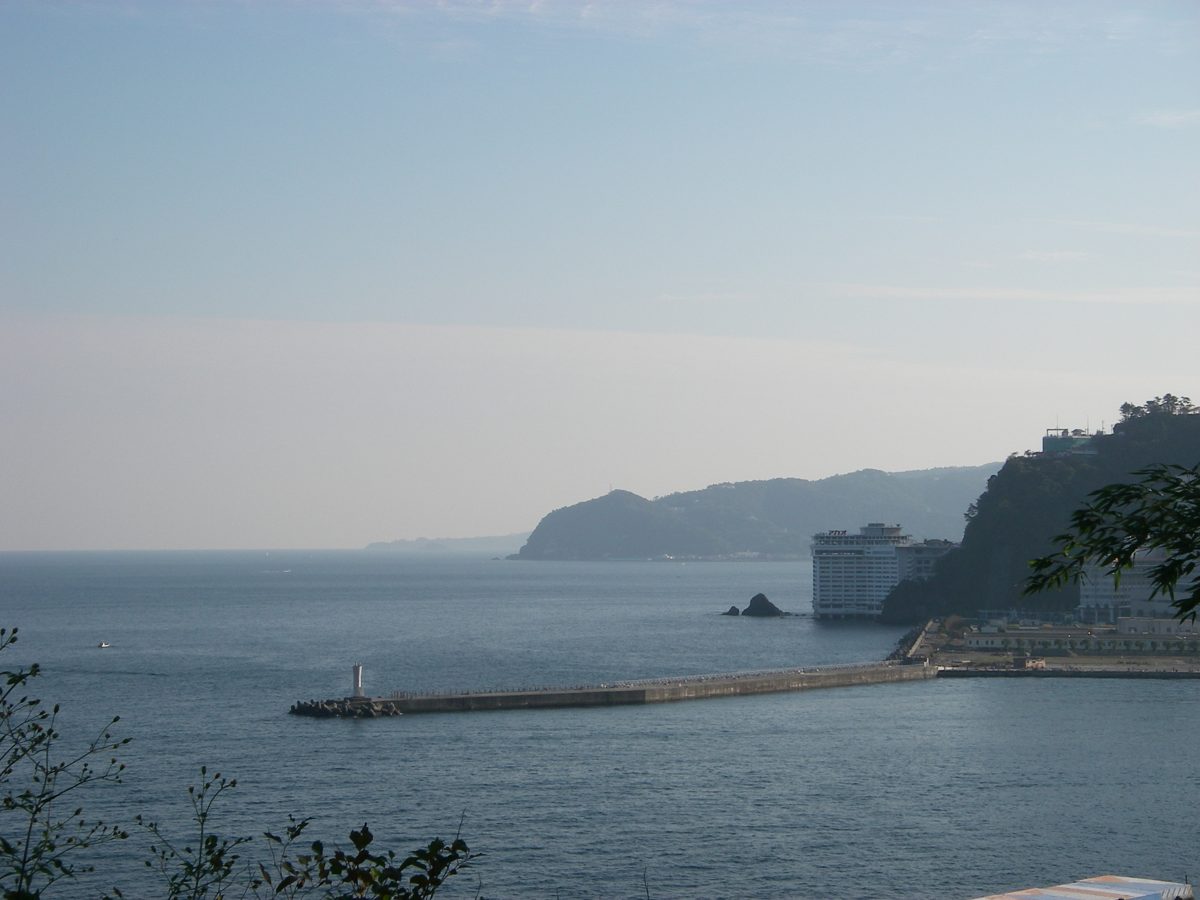 Calm sea off Atami with a breakwater and a wooded headland